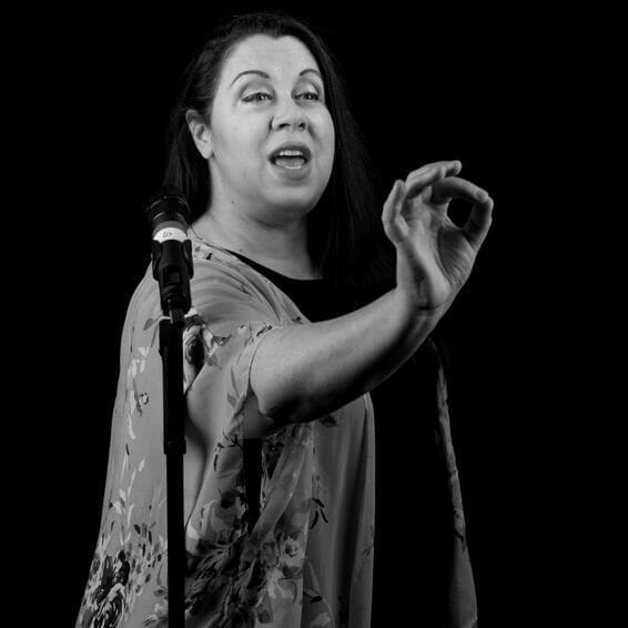 Overview: This black and white photo captures a woman singing passionately into a microphone.
