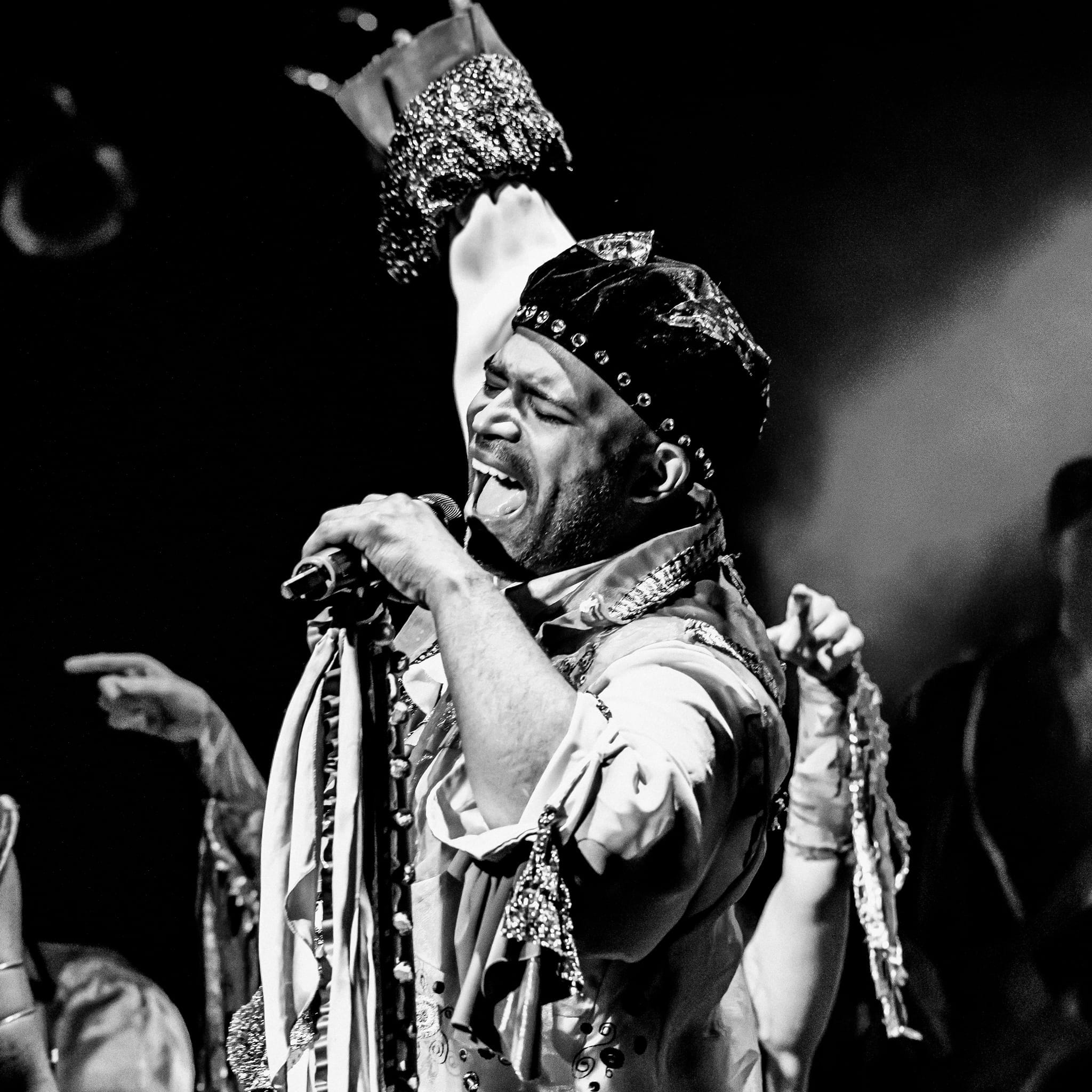 A black and white photo of a man in a dreamy costume singing.